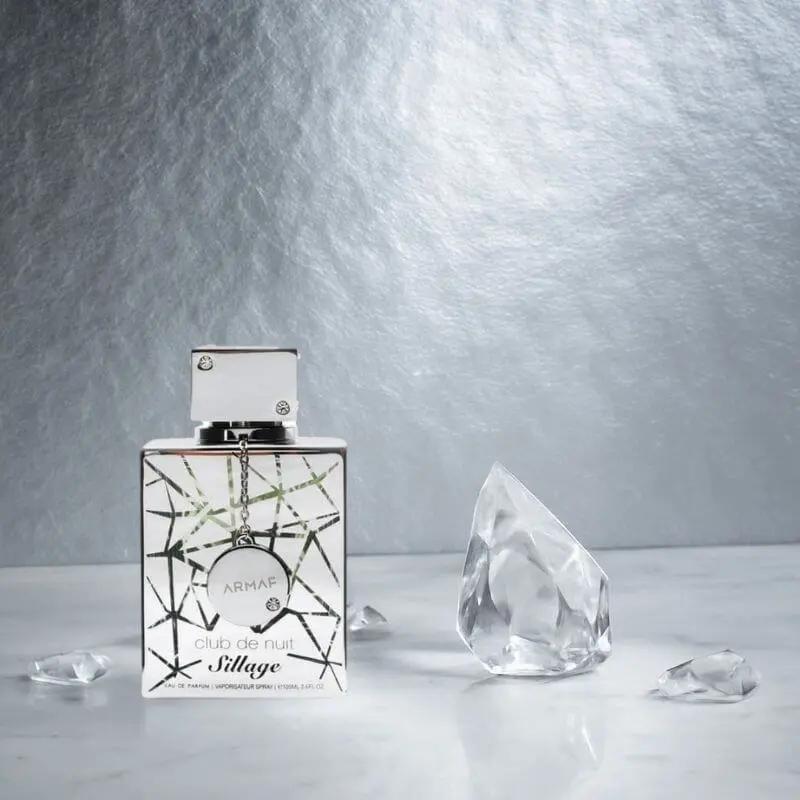 Parfum Armaf Club de Nuit Sillage en flacon argenté, présenté sur fond argent avec des cristaux transparents