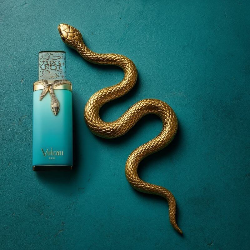Parfum Vulcan de French Avenue en flacon turquoise orné d’un serpent doré, présenté sur un fond bleu élégant